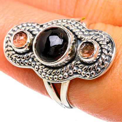 Sterling silver ring featuring dark oval onyx cabochon and two pink gemstone bezels