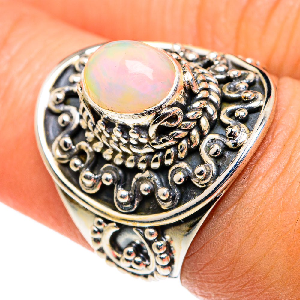 Oval opal cabochon ring with detailed silver filigree, on finger view