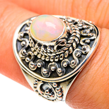 Oval opal cabochon ring with detailed silver filigree, on finger view