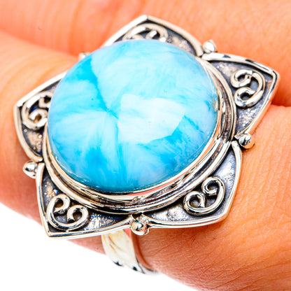 Oval blue larimar cabochon sterling silver ring on finger, ornate filigree sides