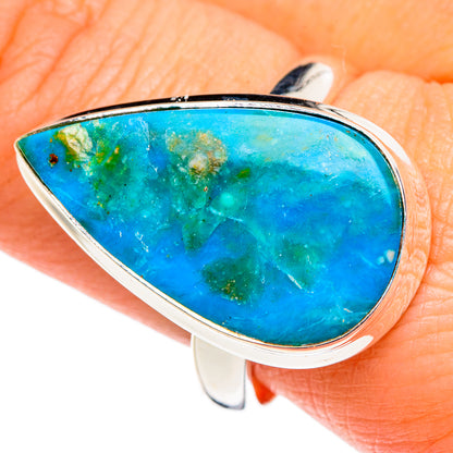 Oval blue opal ring with silver bezel, shown on finger