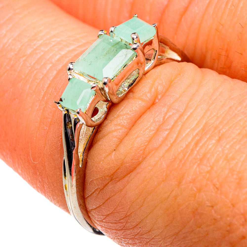 Emerald-green gemstone three-stone sterling silver ring on finger, side view