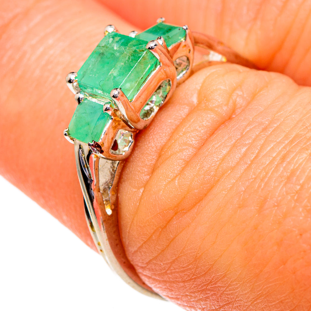 Close-up of emerald green rectangular gemstone ring with three prong-set stones, silver band