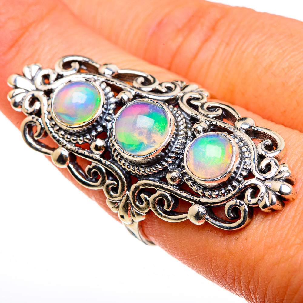 Sterling silver opal ring on finger, three oval iridescent opal cabochons in filigree frame
