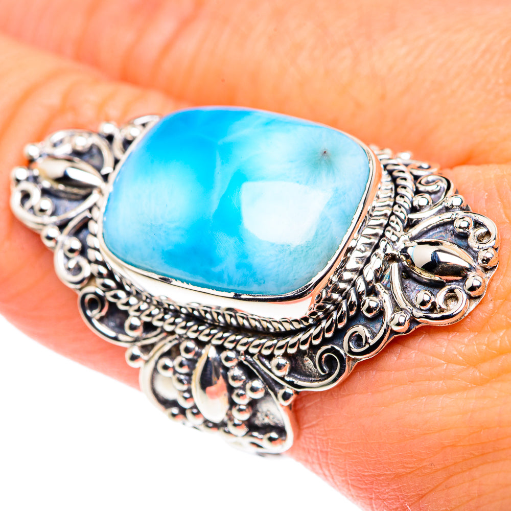 Sterling silver ring with oval blue gemstone and detailed scrolling side accents