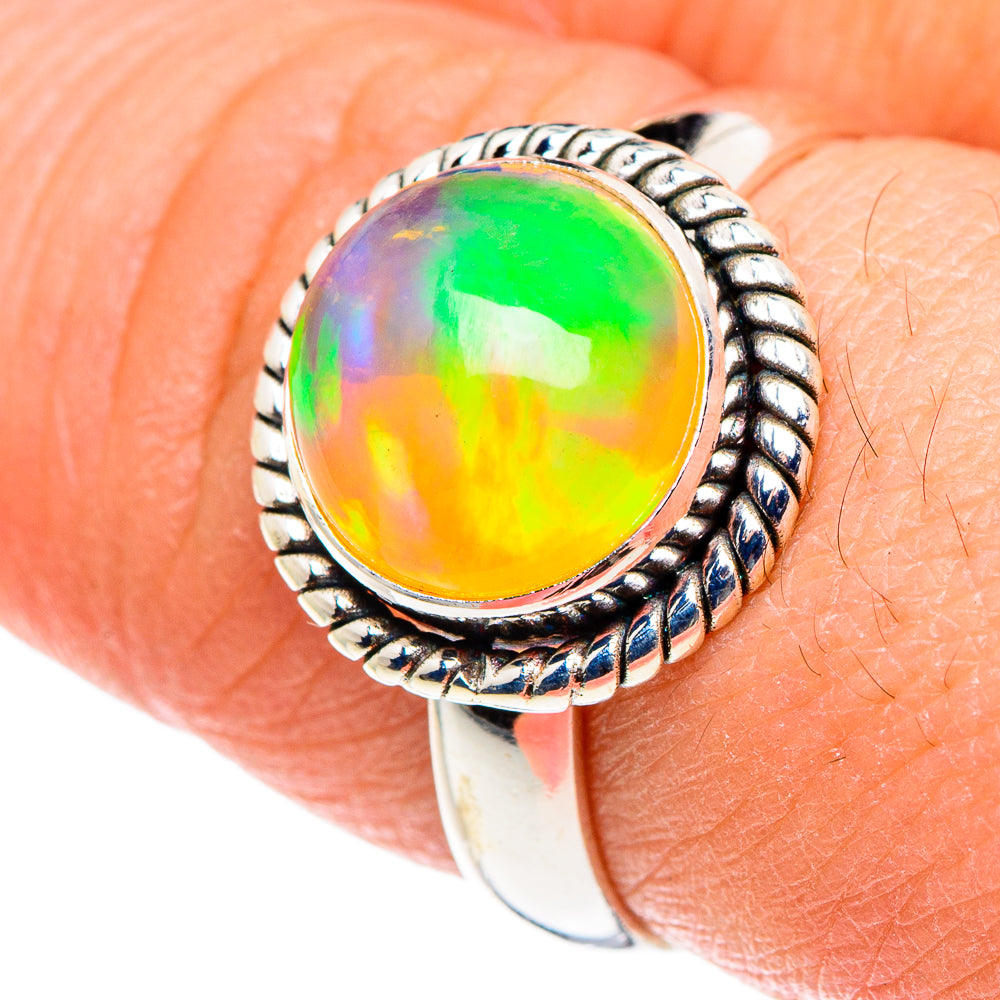 Sterling silver opal ring on finger; oval multicolor Ethiopian opal in rope bezel