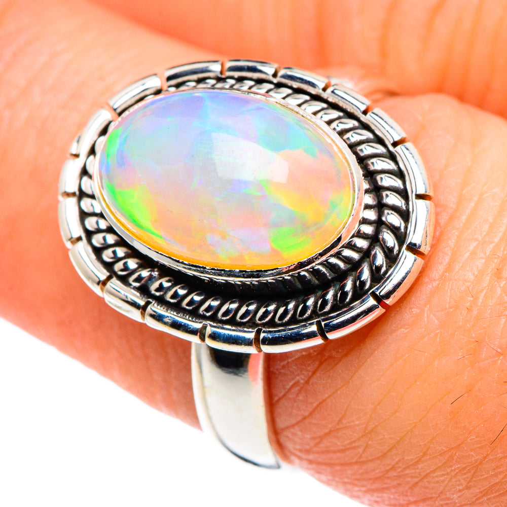 925 sterling silver oval opal ring on finger, iridescent Ethiopian opal face, carved bezel