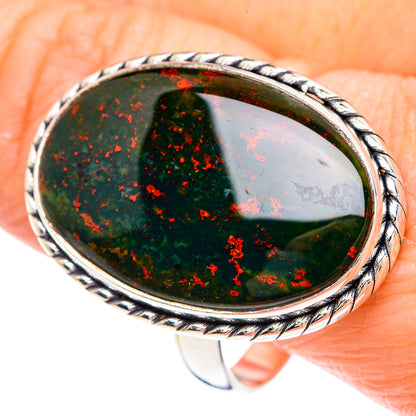 Oval green bloodstone ring with red flecks, twisted silver frame on finger