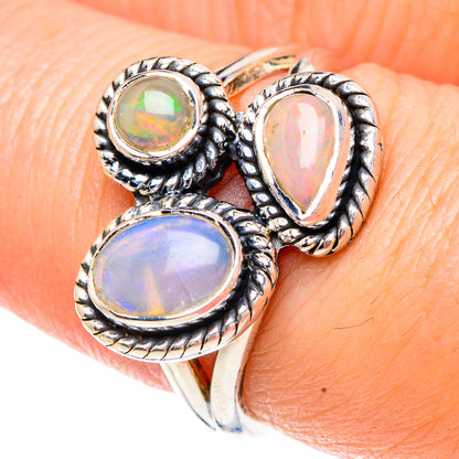 Sterling silver Ethiopian opal ring on finger, three bezel-set cabochons in blue, green, pink