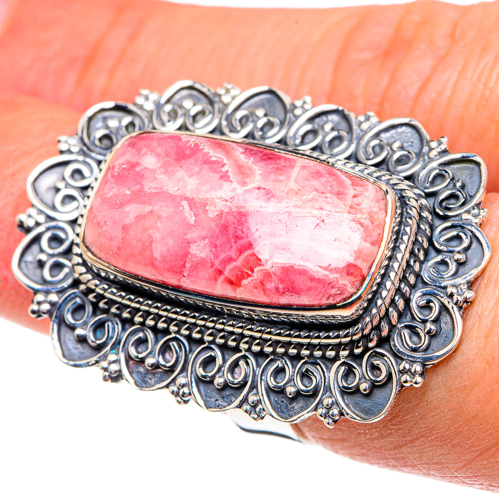 Sterling silver oval rhodochrosite ring on hand with detailed scrolling filigree
