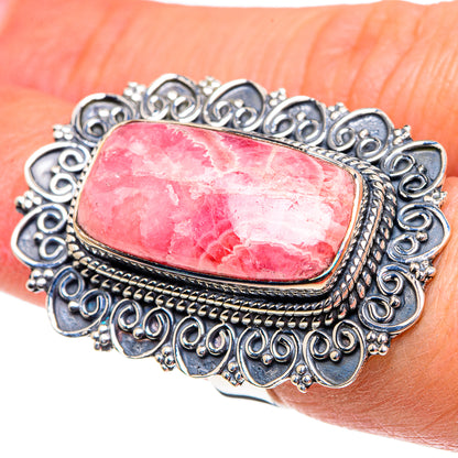 Sterling silver oval rhodochrosite ring on hand with detailed scrolling filigree
