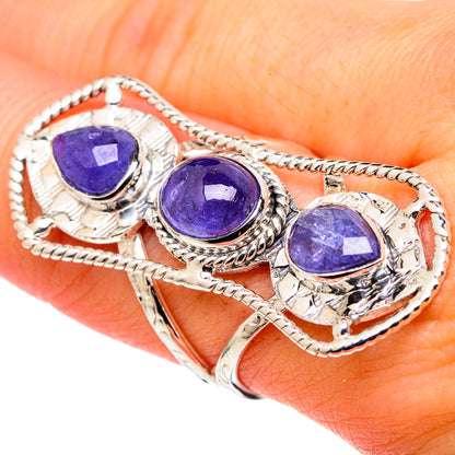 Close-up sterling silver band ring with three oval purple gemstones in ornate braided settings