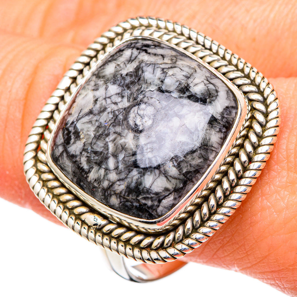Sterling silver oval fossil ring with braided frame, shown close-up on finger
