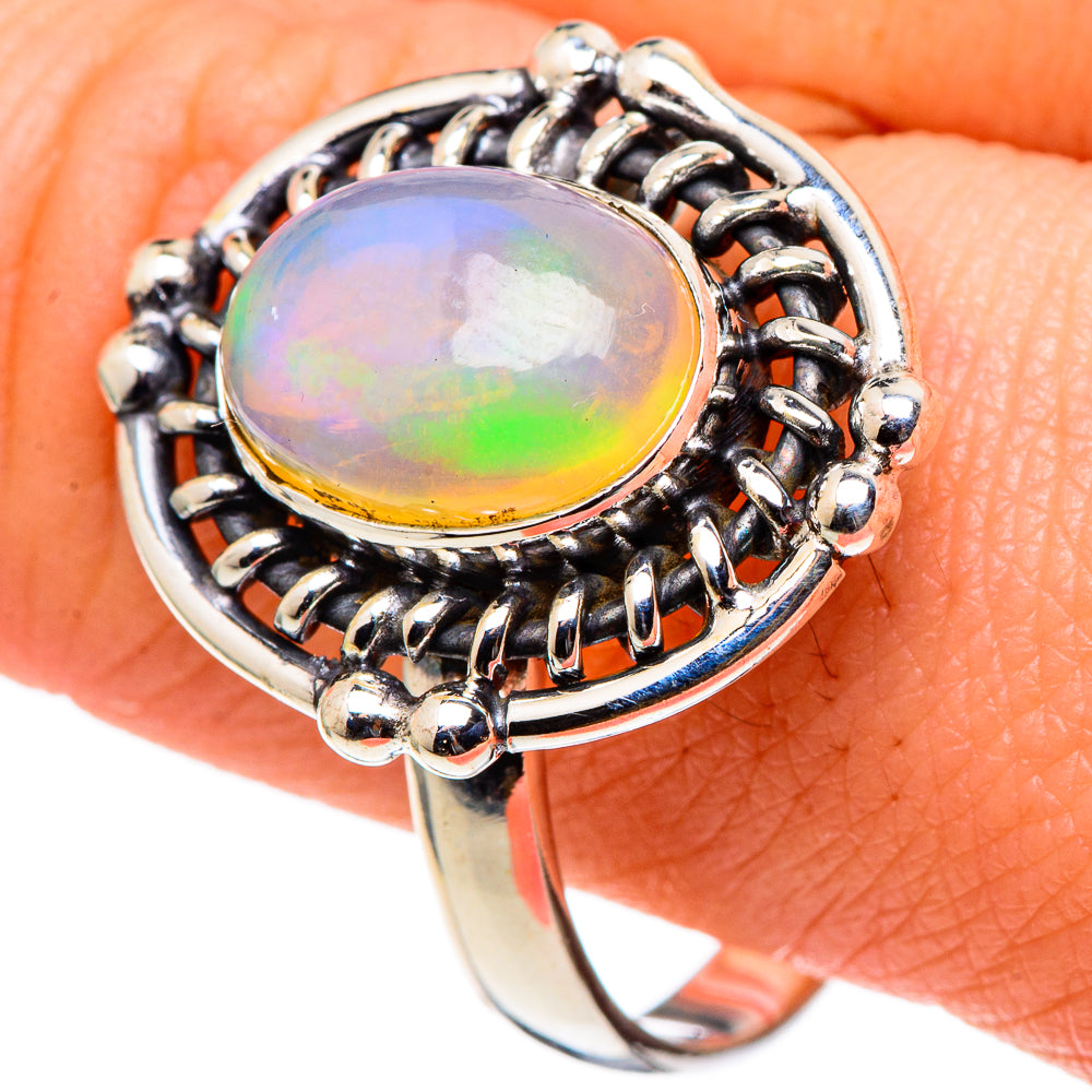Opal ring with oval rainbow cabochon, beaded halo and polished sterling silver band