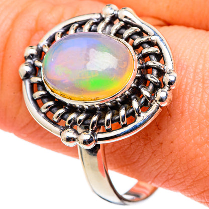 Opal ring with oval rainbow cabochon, beaded halo and polished sterling silver band