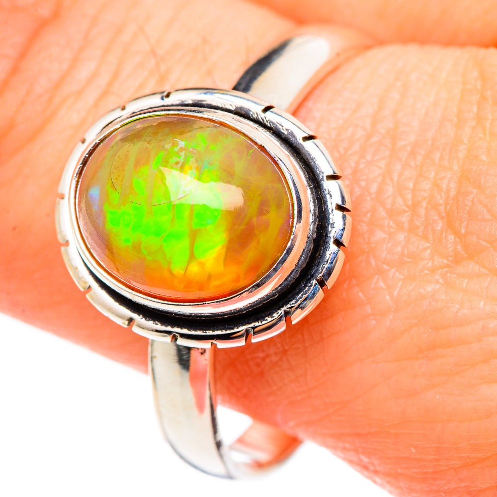 Sterling silver opal ring close-up with round bezel, vivid green fire on orange stone