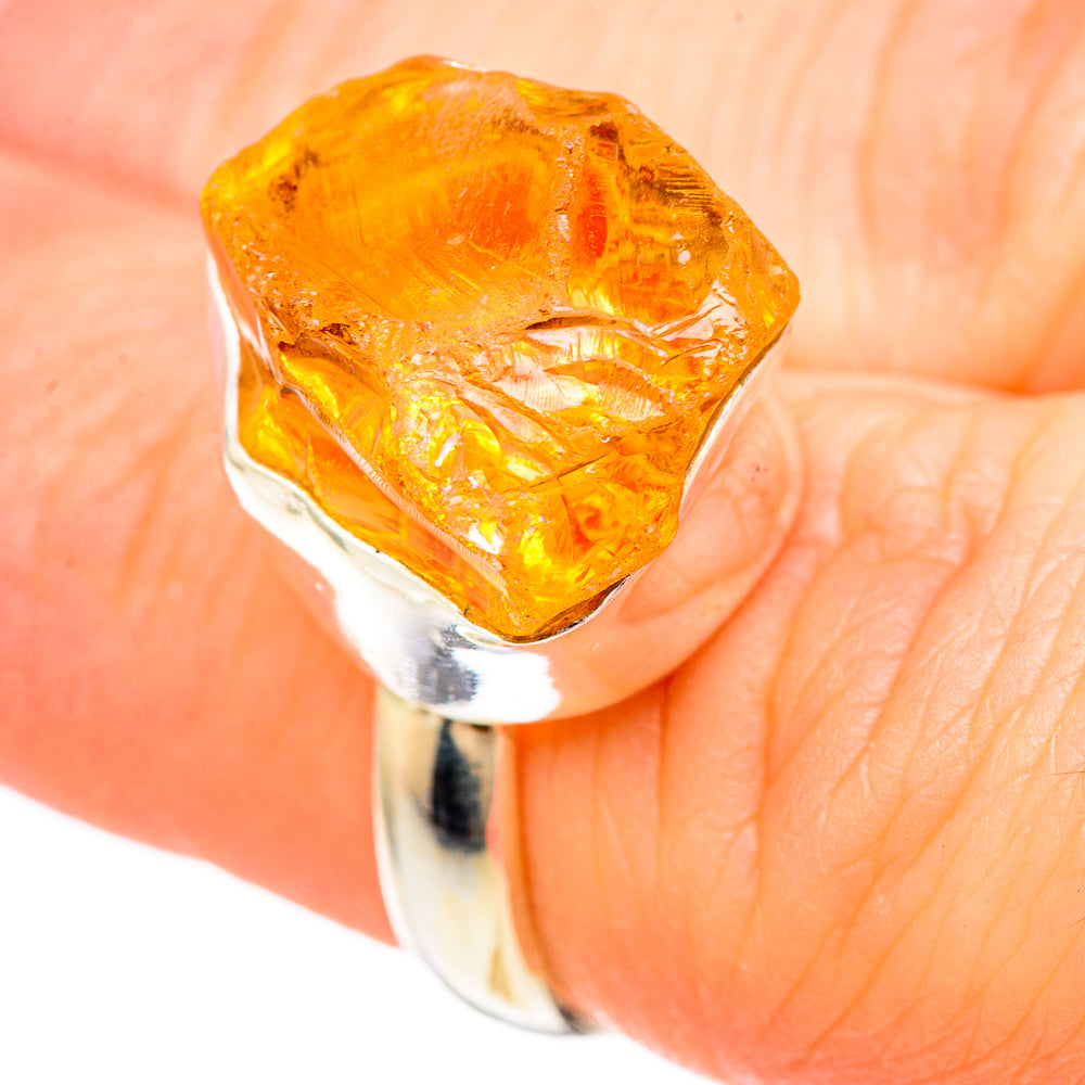 Rough citrine gemstone sterling silver ring on a finger, yellow-orange faceted stone