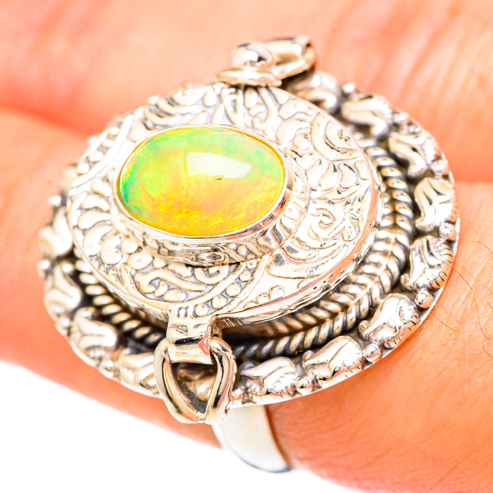 Ornate silver ring on finger with oval green-yellow opal and rope-pattern bezel