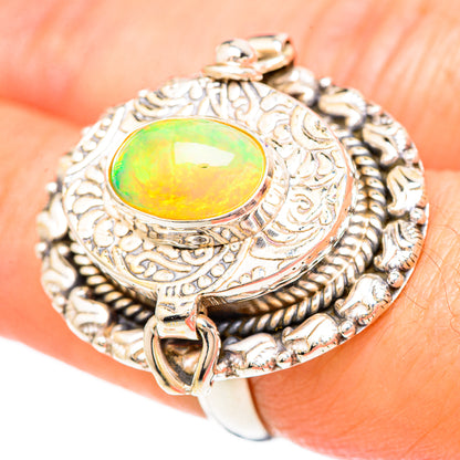 Ornate silver ring on finger with oval green-yellow opal and rope-pattern bezel