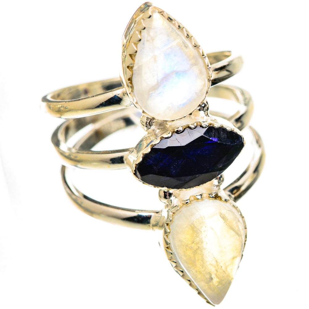 Three-stone iridescent ring with dark faceted center and pear-shaped white stones on silver band