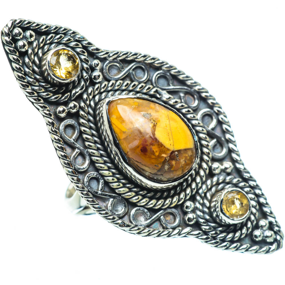 Oval amber gemstone cabochon ring in ornate silver setting with two small yellow stones