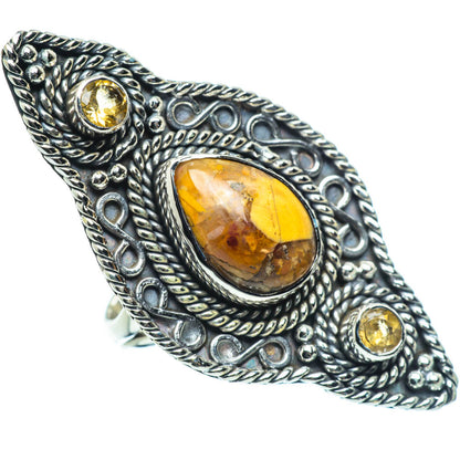 Oval amber gemstone cabochon ring in ornate silver setting with two small yellow stones