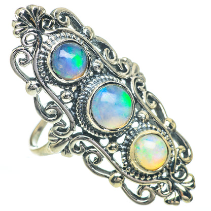 Opal ring with oval multicolor center stone and two smaller stones on scrollwork band