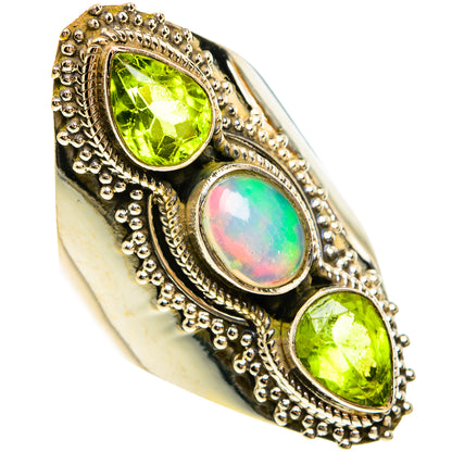 Silver ring with bezel-set green peridot stones and an iridescent opal center