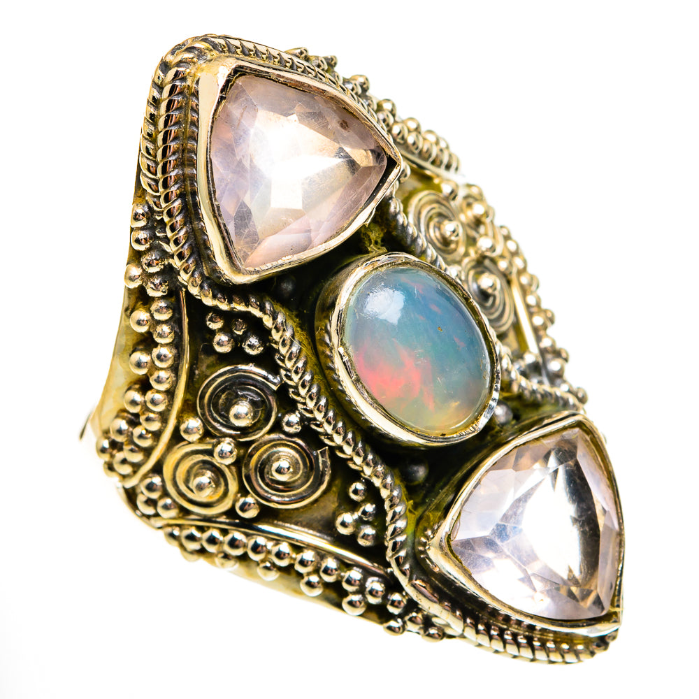 Ornate gold-tone ring with oval opal center and two faceted pink stones