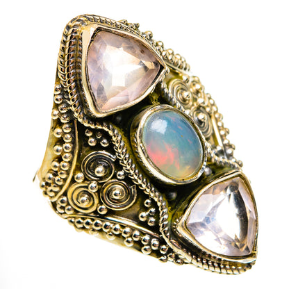 Ornate gold-tone ring with oval opal center and two faceted pink stones