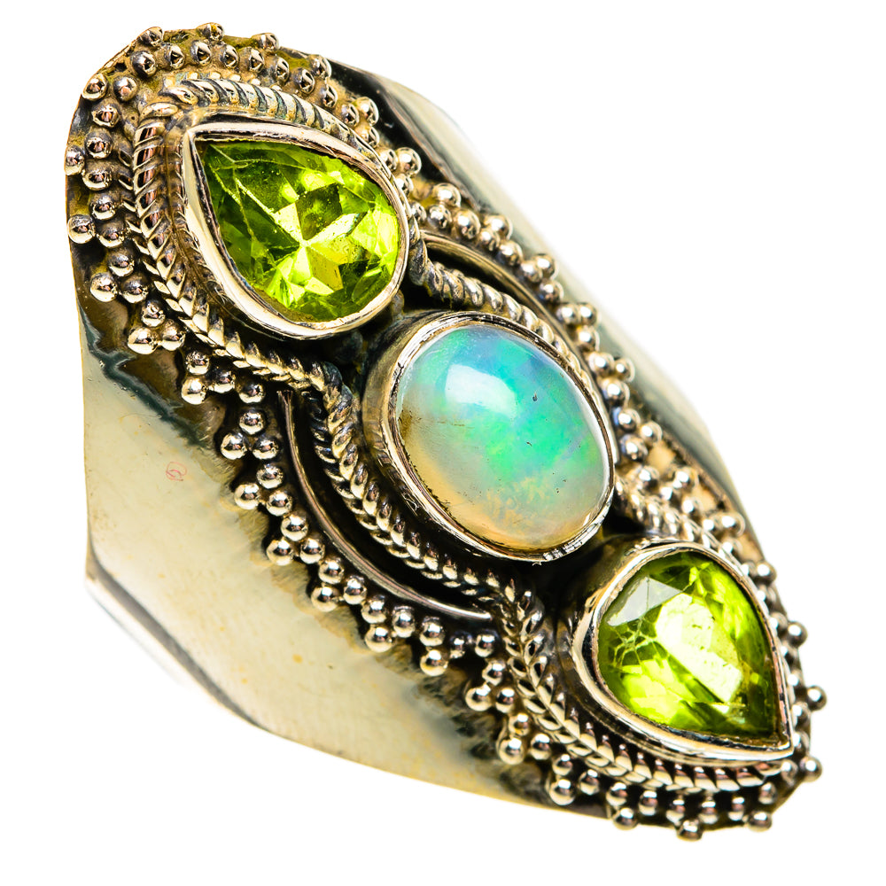 Sterling silver bezel ring with oval opal center, flanked by two green peridot teardrop stones