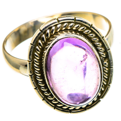 Amethyst oval cabochon ring in gold-tone metal with carved border and purple gem