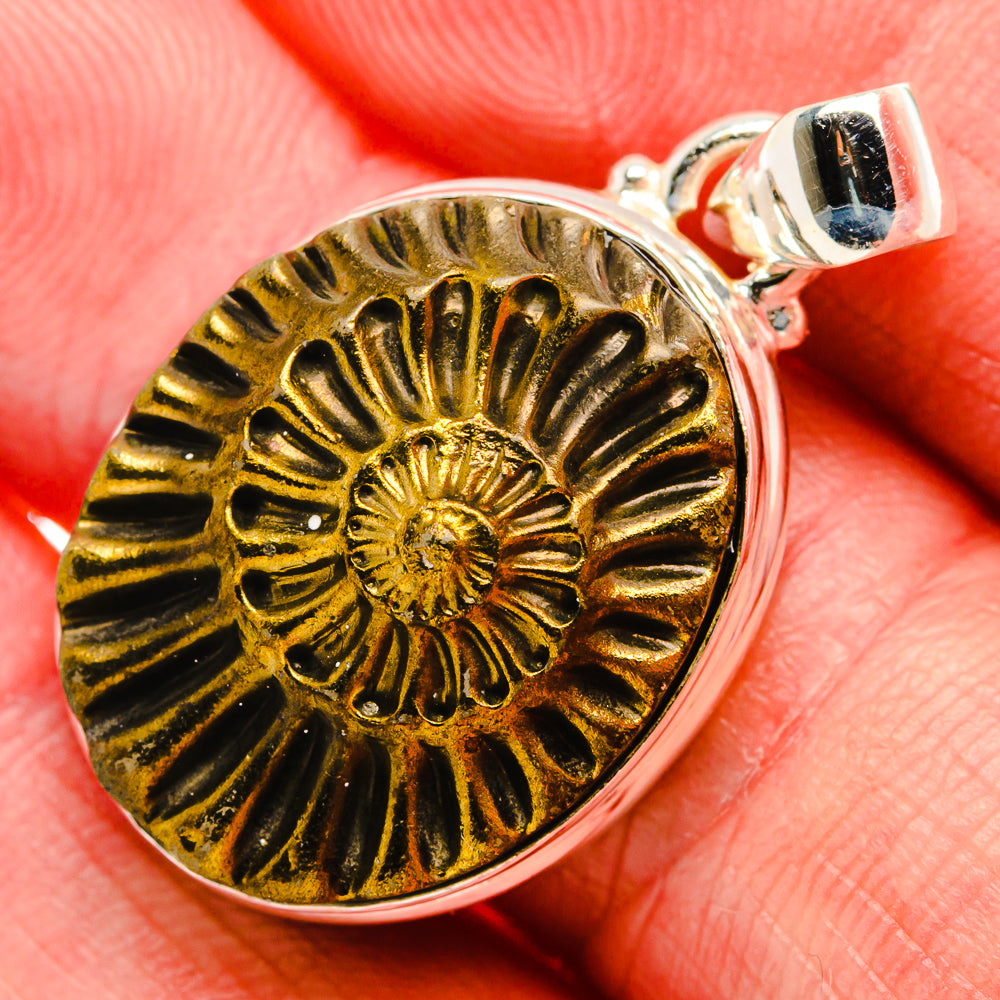 Pyrite fossil pendant in round gold disc with raised spiral detail, silver bail