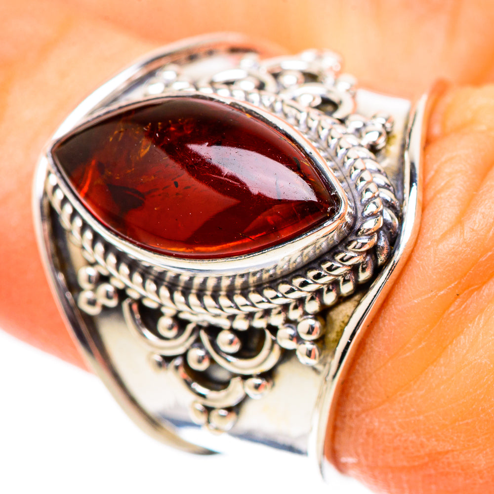 Ornate sterling silver ring with oval red-orange amber stone and filigree setting